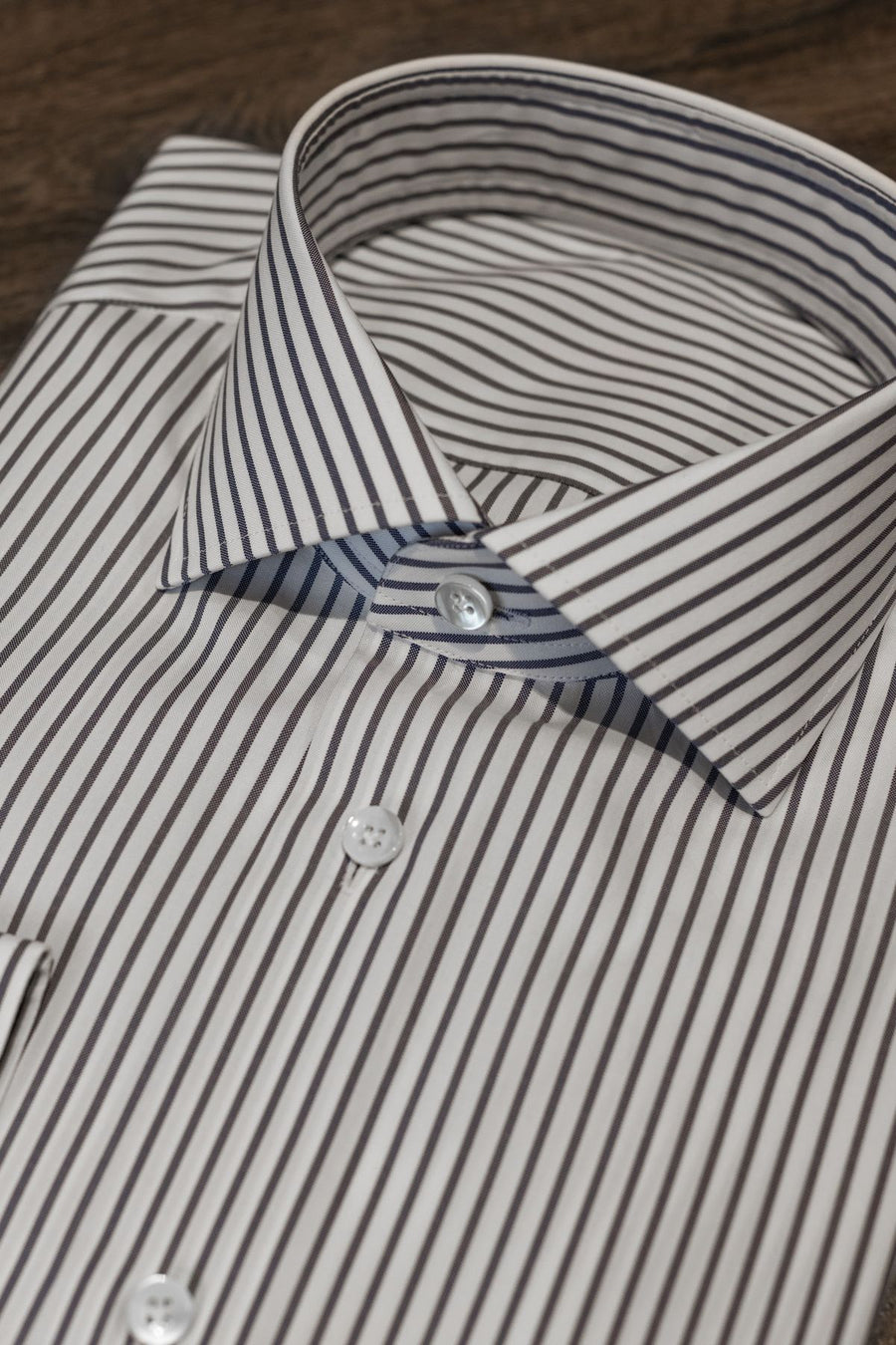 Camisa por medida às riscas cinzentas, dobrada sobre a mesa