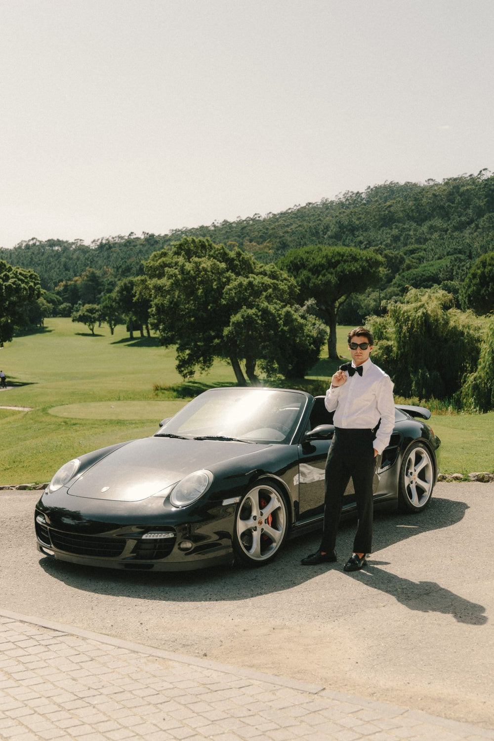 Groom in a tuxedo with a bride by the golf course