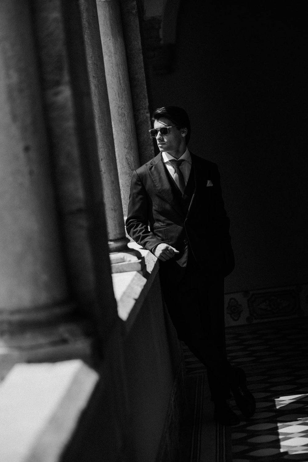 Groom in a navy three-piece by stone arches