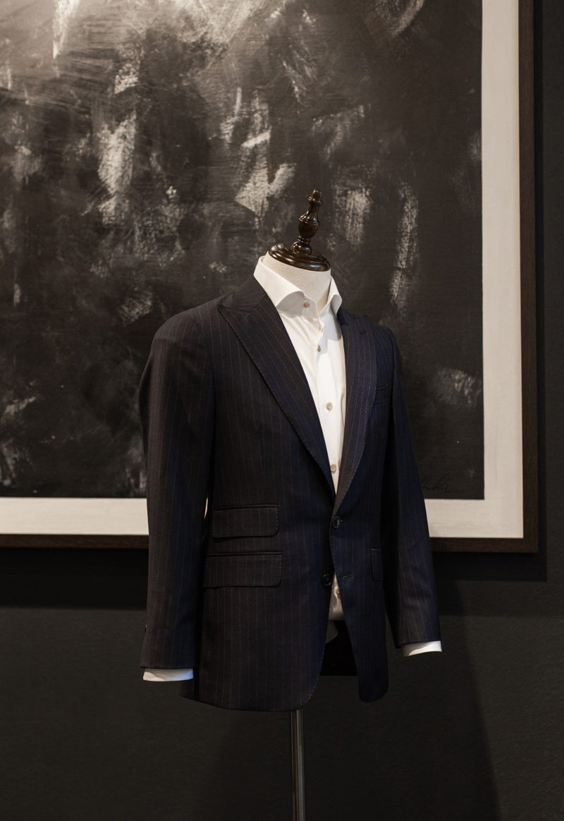Finished navy pinstripe jacket with a white shirt on a stand in the atelier