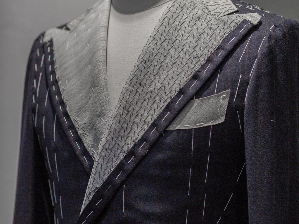 Close-up of hand pad stitching on the lapel canvas of a navy pinstripe jacket