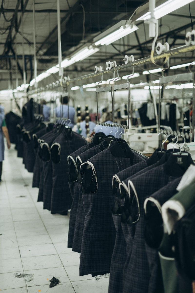 Fila de casacos azul-marinho em cabides na oficina