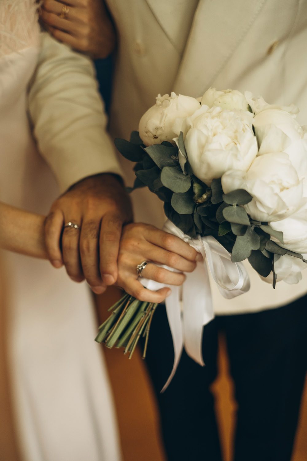 The groom's hands and the bride's bouquet
