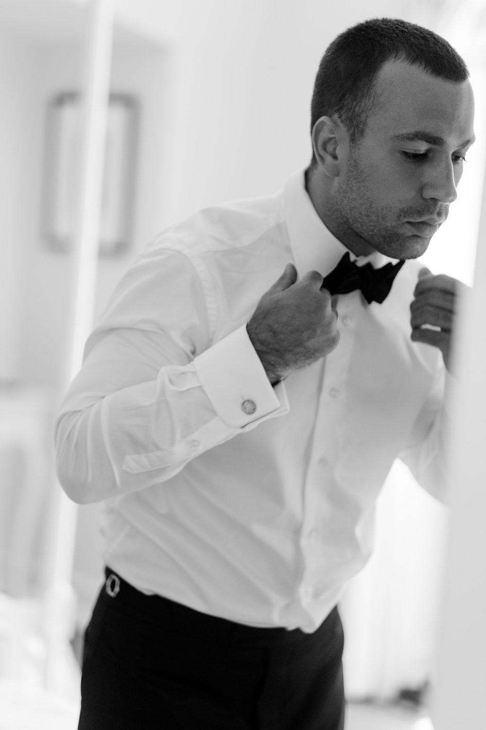 Groom tying a silk bow tie